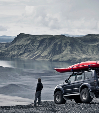 Man Standing in front of jeep with kayak by a lake
