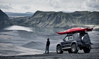 Man Standing in front of jeep with kayak by a lake