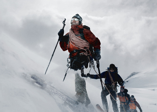 Man leading a team in the snow up a mountain